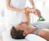 Young man receiving hand massage from therapist at health spa